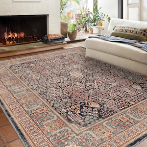 May include: A large, rectangular area rug with an intricate, traditional design. The rug features a dark blue central field with a repeating floral pattern in shades of red, beige, and green. A detailed border frames the design, adding to its classic appeal.