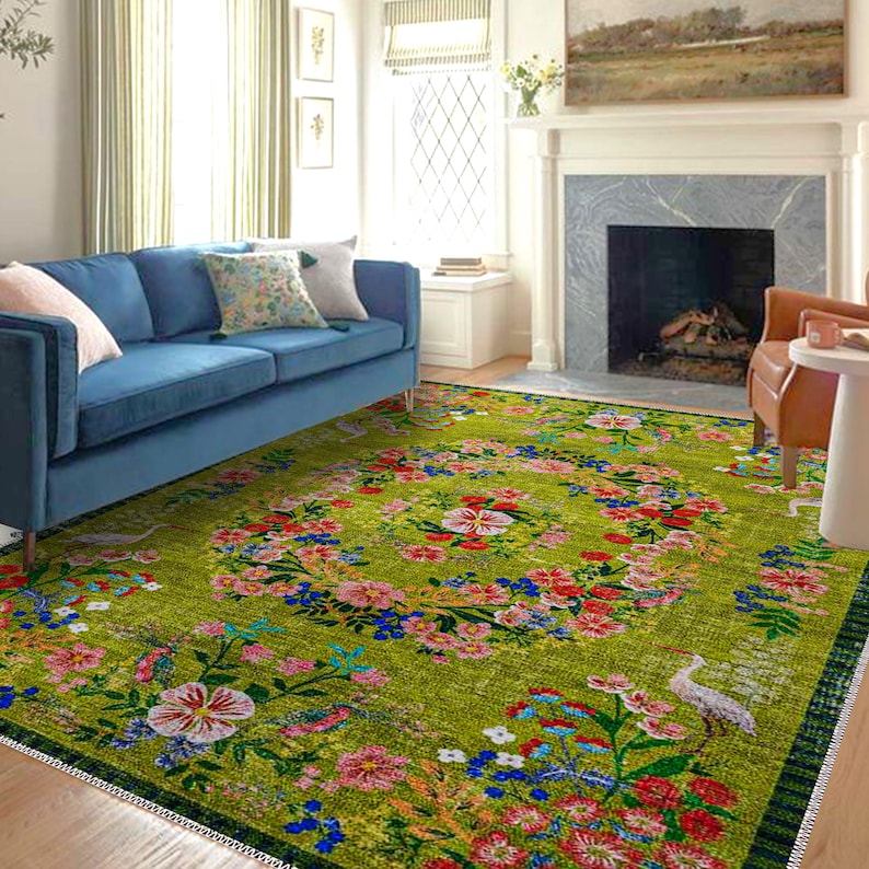 Pode incluir: Um tapete verde vibrante com um design floral. O tapete apresenta um padr&atilde;o circular central de flores vermelhas, rosas e azuis, rodeado por uma borda das mesmas cores. Um sof&aacute; azul e almofadas est&atilde;o no fundo.