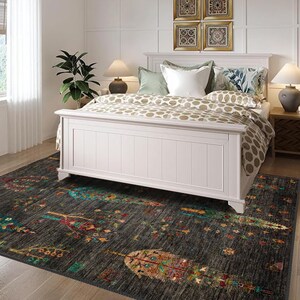 K&ouml;nnte beinhalten: Ein wei&szlig;es Bettgestell mit einer gemusterten Bettdecke und Kissen steht auf einem dunkelgrauen Teppich mit einem bunten Blumendesign. Der Teppich hat ein geometrisches Muster mit B&auml;umen und Blumen.