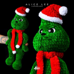 Könnte beinhalten: Ein grünes, gehäkeltes Grinch-Plüschtier, das eine rot-weiße Weihnachtsmütze und einen roten Schal trägt. Das Spielzeug ist handgefertigt und hat einen mürrischen Gesichtsausdruck.