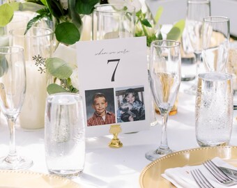 May include: A wedding table setting featuring champagne flutes, water glasses, and gold-edged plates. A table number card with the text "when we were" and the number 7, plus two childhood photos, is displayed.