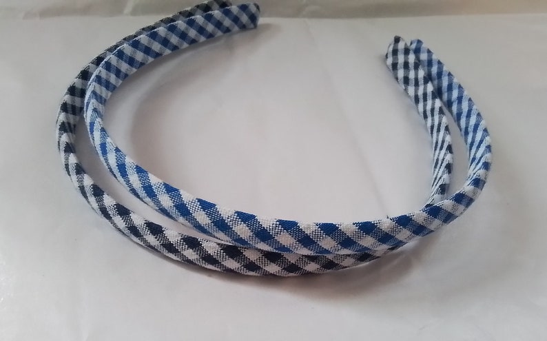 May include: Two fabric-covered headbands, one blue and white gingham and one black and white gingham.