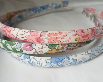 May include: Three floral patterned headbands in blue, green, and pink. The headbands are made of fabric and are designed with a floral pattern.