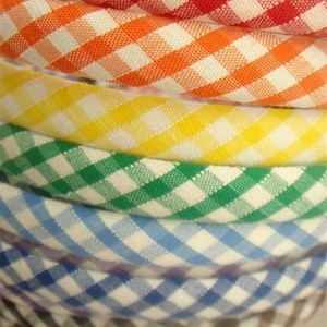 May include: A stack of colorful gingham fabric headbands in red, orange, yellow, green, blue, and brown.