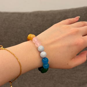 May include: A colorful beaded bracelet with yellow, pink, light blue, dark blue, and green beads.