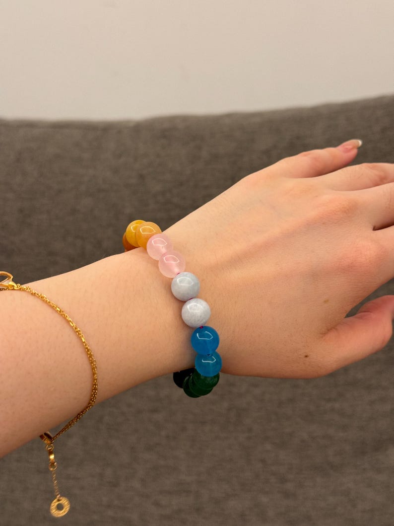 May include: A colorful beaded bracelet with yellow, pink, light blue, dark blue, and green beads.