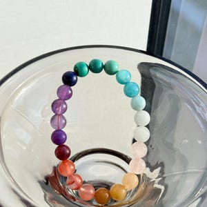 May include: A rainbow colored beaded bracelet with a variety of gemstones, including amethyst, rose quartz, and citrine.