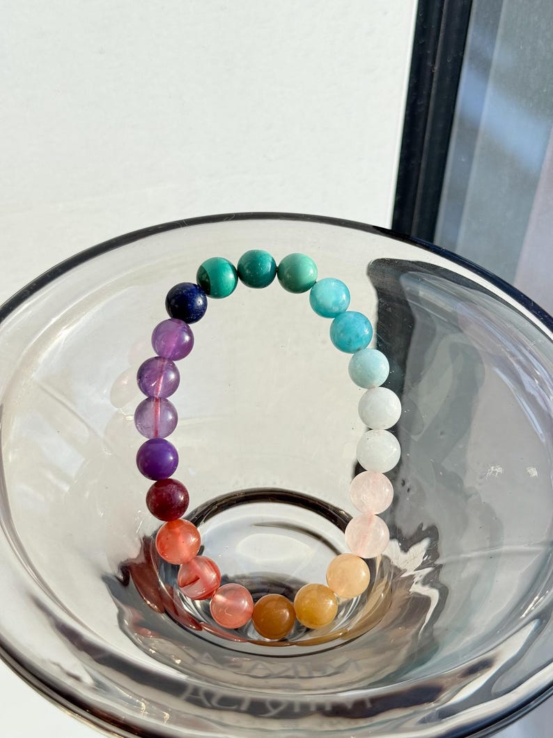 May include: A rainbow colored beaded bracelet with a variety of gemstones, including amethyst, rose quartz, and citrine.