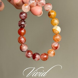 Op de afbeelding: Een armband gemaakt van ronde, doorschijnende kralen in rood, oranje en gele tinten. De kralen hebben een gemarmerd, bewolkt uiterlijk.