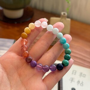 May include: A rainbow gemstone bracelet with beads in shades of yellow, orange, red, purple, blue, and green.