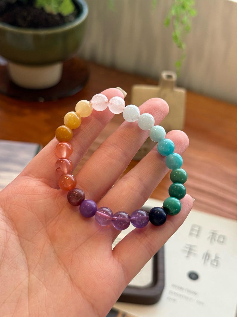 May include: A rainbow gemstone bracelet with beads in shades of yellow, orange, red, purple, blue, and green.