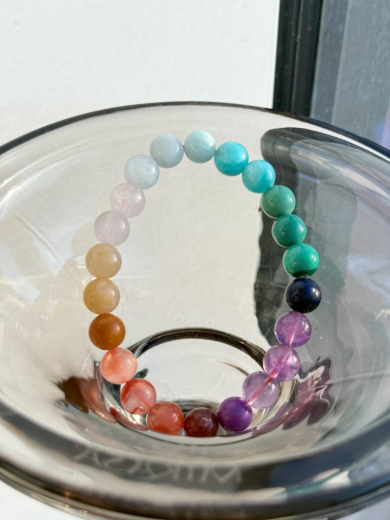 May include: A rainbow gemstone bracelet with beads in shades of pink, orange, red, green, blue, and purple.
