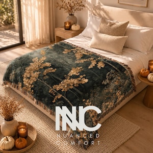 May include: A woven throw blanket featuring a dark forest scene with golden autumn leaves, finished with a fringed edge. The blanket is draped over a bed with white bedding and pillows. The text NNC is overlaid in white in the centre.