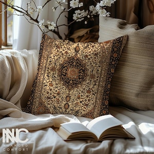 Könnte beinhalten: Ein dekoratives Kissen mit cremefarbenem Hintergrund und einem schwarzen, braunen und orangefarbenen Blumenmuster. Das Kissen liegt auf einem Sofa mit einem Buch und einer Decke.
