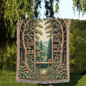 May include: A woven tapestry throw blanket featuring a forest scene with a bookshelf in the center. The bookshelf is filled with books and the forest is lush and green. The tapestry is framed with a brown border and has fringe on the edges.
