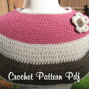 Puede incluir: Una capa de ganchillo en tonos rosa, crema y marrón, adornada con una aplicación de flores. La capa presenta rayas horizontales y se muestra en un maniquí. El texto "Crochet Pattern Pdf" es visible.