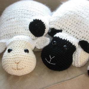 May include: Two crocheted sheep plushies, one white with black accents and one black with white accents. Both have black eyes and a stitched smile.