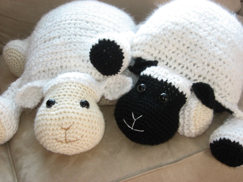 May include: Two crocheted sheep plushies, one white with black accents and one black with white accents. Both have black eyes and a stitched smile.