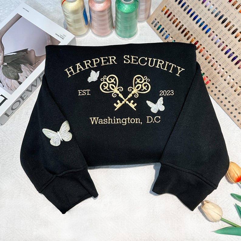 May include: Black sweatshirt with gold embroidery featuring the text "HARPER SECURITY EST. 2023 Washington, D.C." with two crossed keys and butterflies.