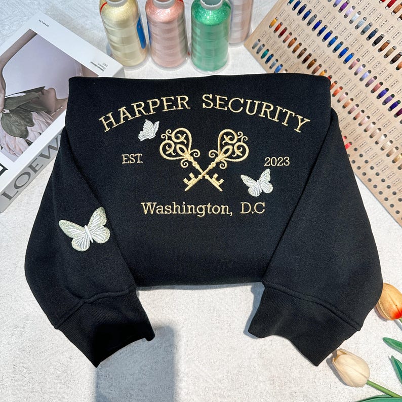 May include: Black sweatshirt with gold embroidery of two keys crossed, the text "HARPER SECURITY", "EST. 2023", and "Washington, D.C.", and three white embroidered butterflies.
