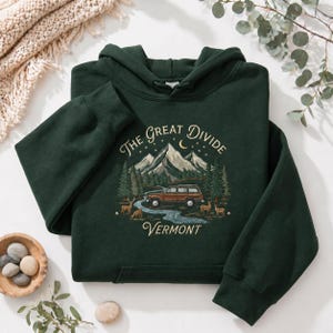 Può includere: Felpa con cappuccio verde scuro con un design grafico raffigurante montagne, un'auto, alberi e cervi. Il testo recita "The Great Divide Vermont". La felpa con cappuccio ha un cappuccio e maniche lunghe.