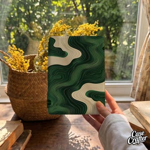 May include: A rectangular e-reader cover featuring a topographic map pattern with flowing, layered lines in shades of deep forest green, emerald, and cream. The design creates a fluid, abstract landscape effect across the entire surface.