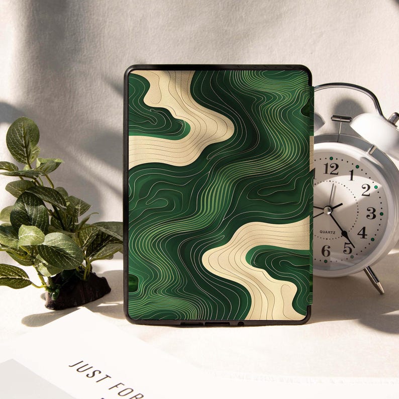 May include: A black tablet case with a green and beige topographic design. The case has a modern look with a detailed, layered pattern. The design resembles a map with contour lines. The case is displayed on a white surface.