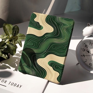 May include: A rectangular case featuring a green and beige topographic design. The case has a curved, layered pattern in shades of green and beige. The text "FOR TODAY" is visible on a white surface in the background.