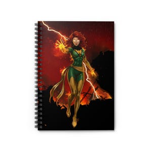 May include: Spiral-bound notebook featuring a comic book illustration of a red-haired superheroine in a green and gold costume. The character is surrounded by lightning and flames against a red and black background.