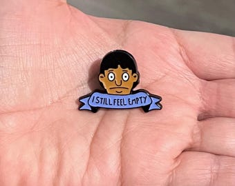 Pin esmaltado de Bob's Burgers - Divertido pin de metal de Gene Belcher con la frase "Tengo hambre, todavía me siento vacío" de la serie de televisión.