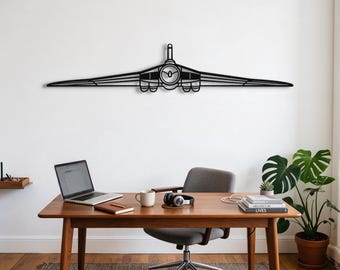 May include: A black metal wall art piece shaped like a stylised aeroplane silhouette with a central circular engine detail and long, thin wings extending horizontally, mounted on a plain white wall above a wooden desk and office chair.