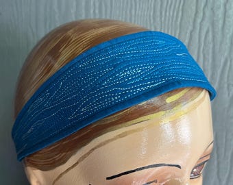 Pode incluir: Uma faixa de cabeça azul com um design estampado branco. A faixa de cabeça é feita de tecido e é acolchoada.