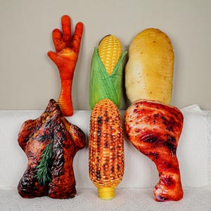 May include: A selection of plush food toys, including a chicken foot, sweetcorn, a loaf of bread, a roasted chicken, a cob of corn, and a roasted chicken leg. The toys are designed to resemble realistic food items.