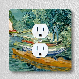 May include: A double electrical outlet cover featuring a painting of boats on a river, in the style of Van Gogh. The artwork is predominantly blue, green, and yellow, with white outlets. The painting depicts a man standing on a boat.