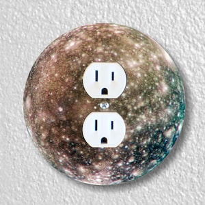May include: A round wall plate with a brown, green, and white image of Jupiter. The plate has two standard electrical outlets.