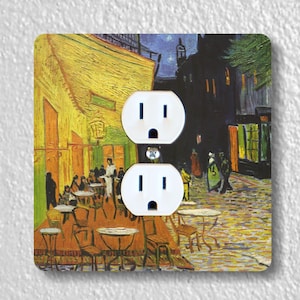 May include: A white double outlet wall plate with a decorative image of Vincent van Gogh's painting "Cafe Terrace at Night". The painting depicts a cafe terrace with people sitting at tables under a starry night sky.