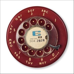 May include: A red rotary dial phone with a clear plastic faceplate and a white label with the text "CENTEL 919 AREA CODE 364-2828".