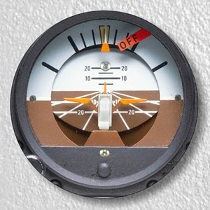 May include: A round, black and brown instrument with a white face and a needle pointing to the center. The instrument has a switch labeled "OFF" and markings for 20 degrees.