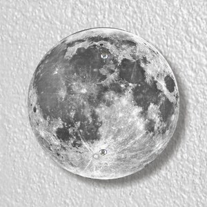 May include: A black and white photograph of the moon, showing its surface with craters and other features.