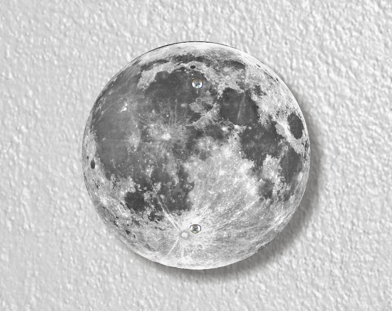 May include: A black and white photograph of the moon, showing its surface with craters and other features.