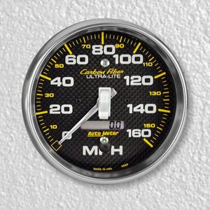 May include: A black and yellow speedometer with a carbon fiber face. The gauge reads up to 160 mph and has a digital display that reads 0.0. The gauge is labeled "Carbon Fiber Ultra-Lite" and "Auto Meter".