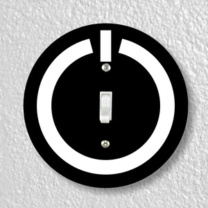 May include: Black and white light switch cover with a white circle around a black power button symbol.