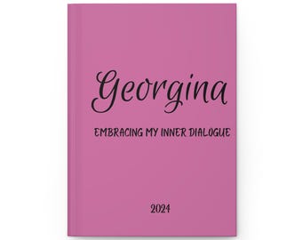 May include: A pink journal with the name "Georgina" written in cursive script. The text "Embracing My Inner Dialogue" is printed below the name. The year "2024" is printed at the bottom of the journal.