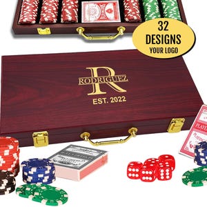 May include: A dark wood poker set case with gold latches and a handle, featuring the gold text "RODRIGUEZ" and "EST. 2022" on the lid. The set includes stacks of red, blue, green, and black poker chips, red dice, and decks of playing cards.