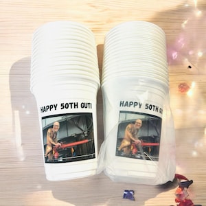 May include: A stack of white plastic cups with a personalized design. The cups feature a photo of a man and the text "Happy 50th Guti".