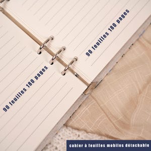 May include: Open notebook with lined pages and metal ring binder. The text "90 feuilles 180 pages" is printed in blue on the pages. The bottom of the image has the text "cahier &agrave; feuilles mobiles d&eacute;tachable".