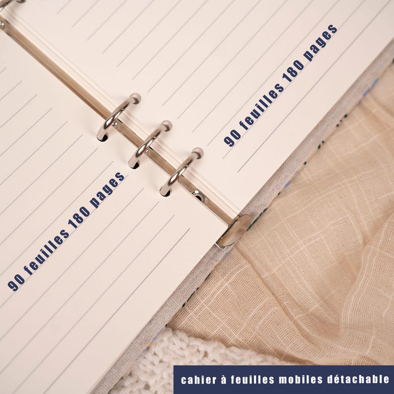 May include: Open notebook with lined pages and metal ring binder. The text "90 feuilles 180 pages" is printed in blue on the pages. The bottom of the image has the text "cahier &agrave; feuilles mobiles d&eacute;tachable".