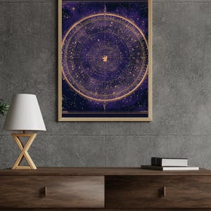 May include: A framed celestial map print with a deep purple and gold color scheme. The artwork features a detailed circular design of constellations and stars. The print is displayed on a dark wooden console table, with a lamp and books.