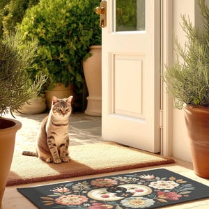 Witchy outdoor doormat featuring a central all-seeing eye, crescent moons, and floral details in an embroidery-style design. This weatherproof welcome mat measures 26x18 inches and is ideal for porches or patio entries. Symbolic celestial motifs offer intuitive protection and spiritual elegance for magical home decor.