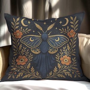 Peut inclure: Coussin décoratif avec un fond bleu foncé orné d'un motif de papillon détaillé. Le papillon a des ailes bleues et dorées, entourées d'éléments floraux et célestes dorés. Des fleurs orange et des croissants de lune complètent le design.